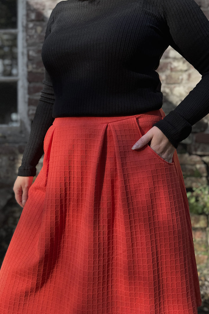 Lähikuva oranssista Armi-hameesta. Materiaalin pinnassa on kaunis ruutukuviointi.